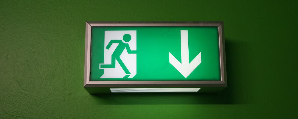 Ein grünes "Rettungsweg-Schild" , angebracht auf einer grünen Wand.